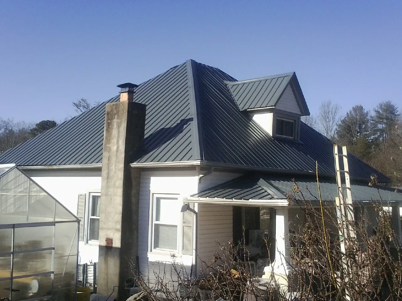 Dark blue standing seam metal roof on a white farmhouse with dormer — Slate & Tile Roof Repair by Roofing Brothers in Ipava