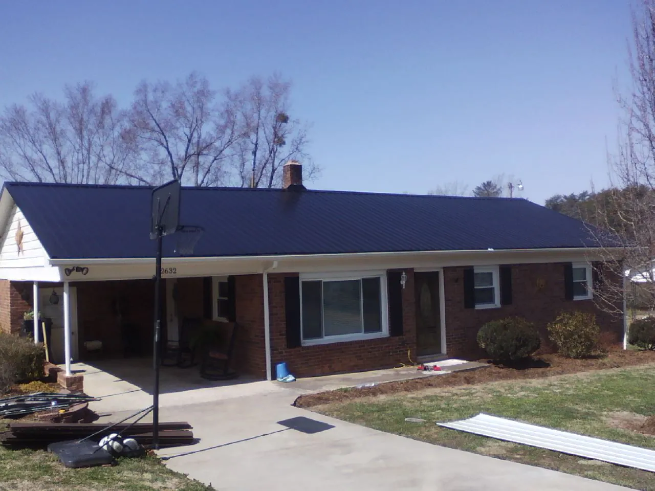 Finished dark blue metal roof on a brick ranch with a carport in Ipava