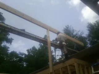 Carpenter setting a ridge beam over a new addition frame — Ice Dam Removal by Roofing Brothers in Ipava