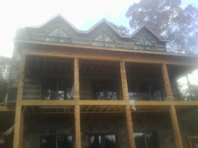 Dormers and porch framing on a large log home under construction — Roof Coating work by our crew in Ipava