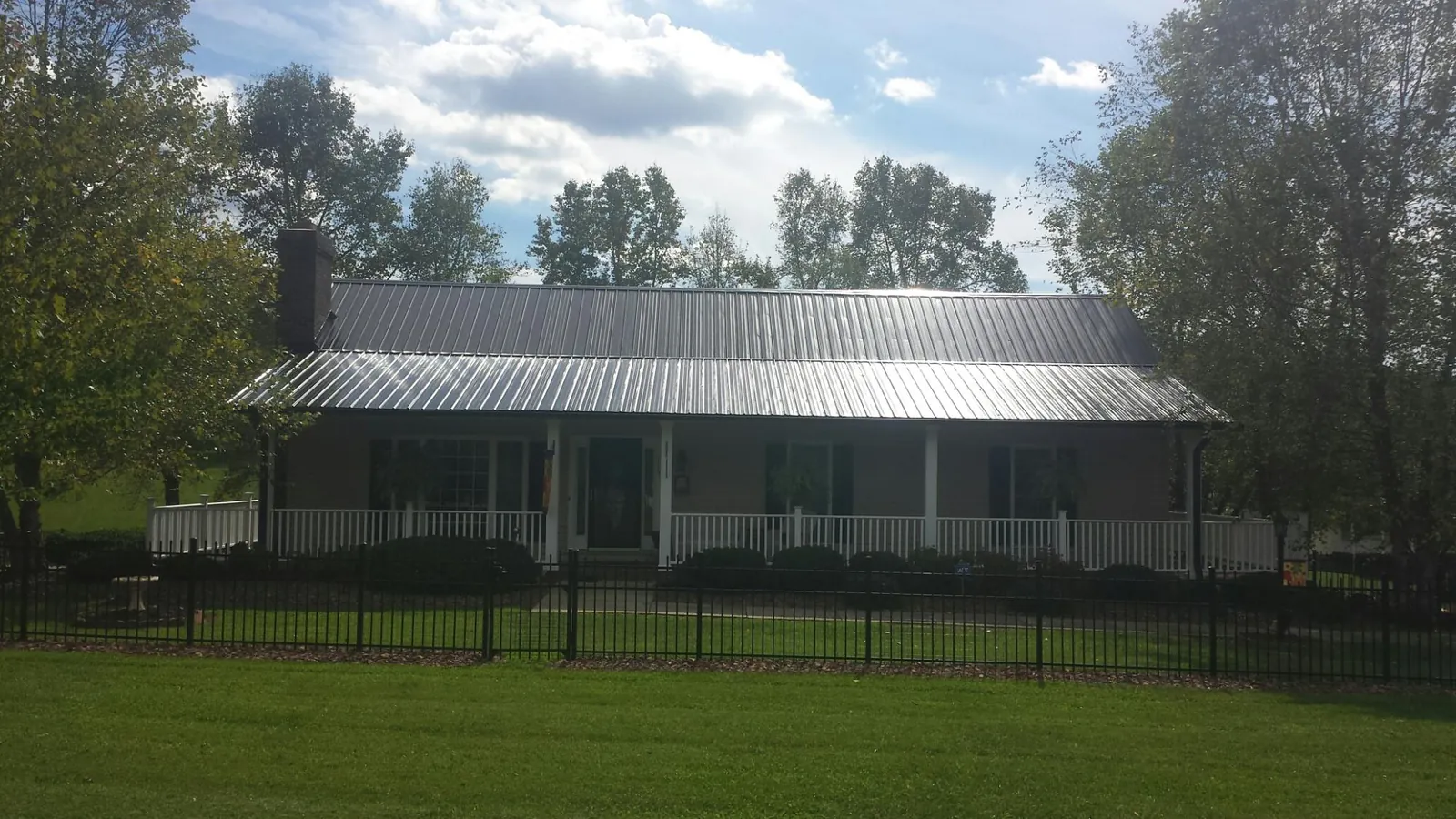 Gray metal roof on a brick ranch with a full width front porch — Gutter Guard Installation work by our crew in Ipava