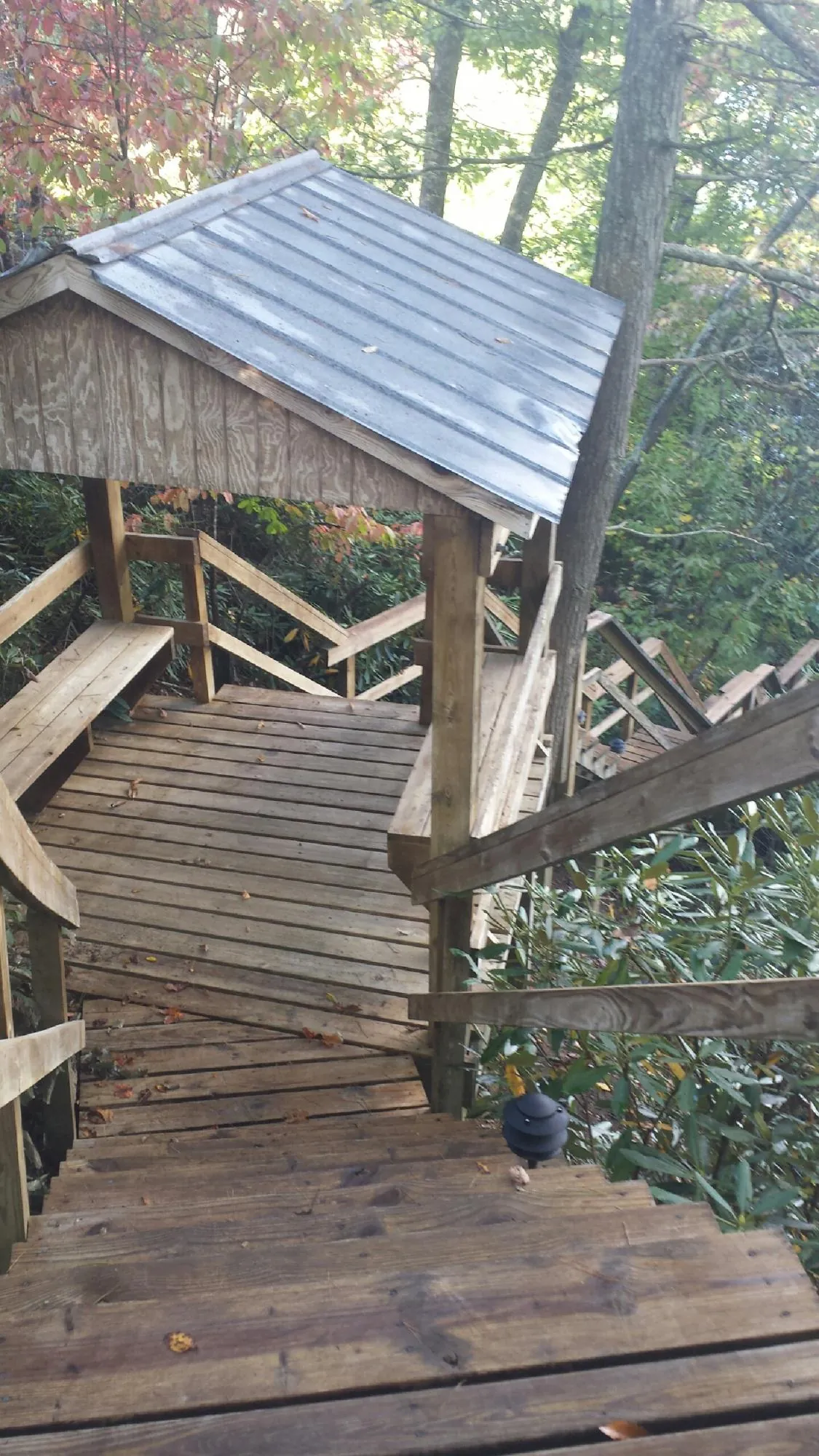 Metal roofed shelter over wooden steps on a wooded walkway — Skylight Repair & Installation work by our crew in Ipava