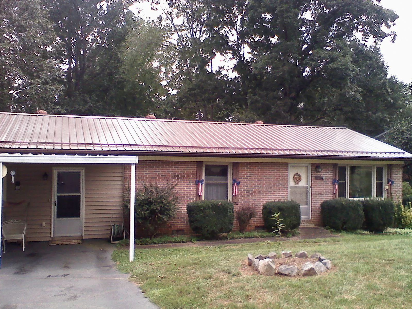 Bronze metal roof and carport on a brick ranch home — Roof Repair work by our crew in Ipava