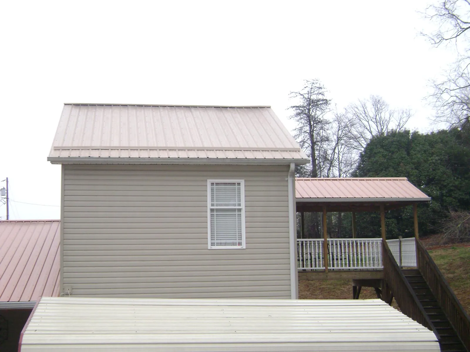 Tan metal roofs on a two story addition and attached porch, from a Roof Replacement job in Ipava
