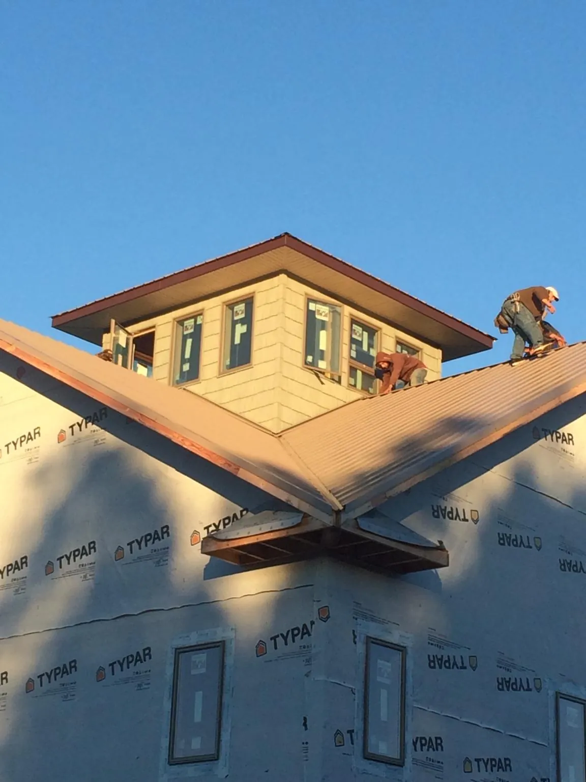 Roofers working around a rooftop cupola on a new metal roof at sunset — Roof Waterproofing in Ipava by Roofing Brothers